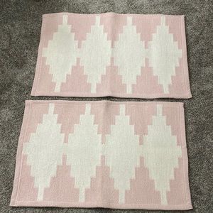 Set of two 20”x34” rugs by Home Essentials. Color is a soft pink and white.
